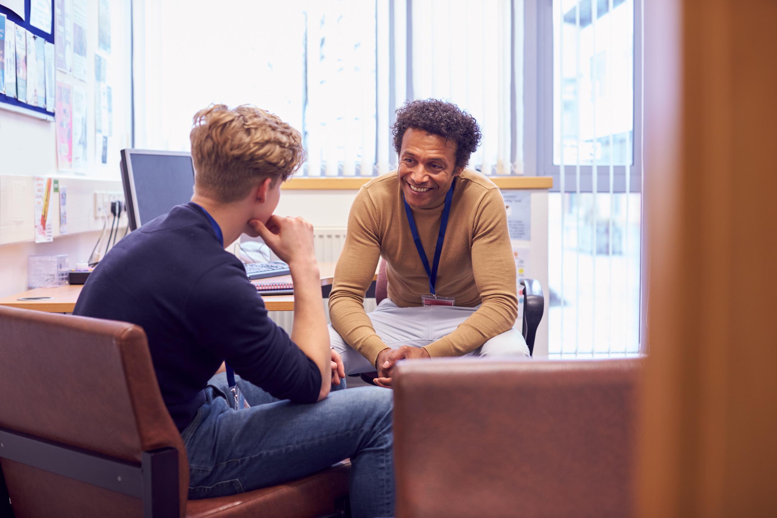 male college student meeting with campus counselor